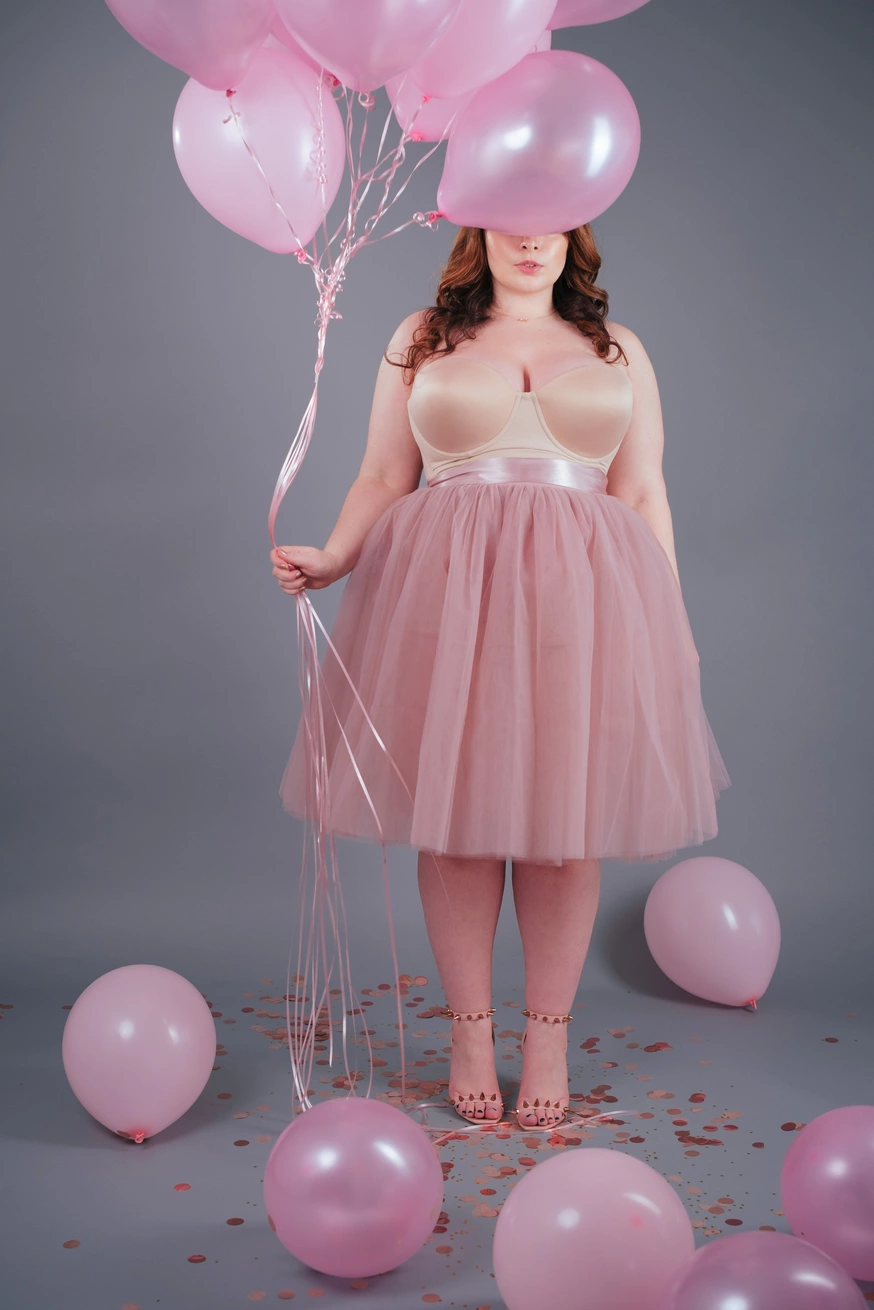 model in pink tulle skirt and bustier holding pink balloons